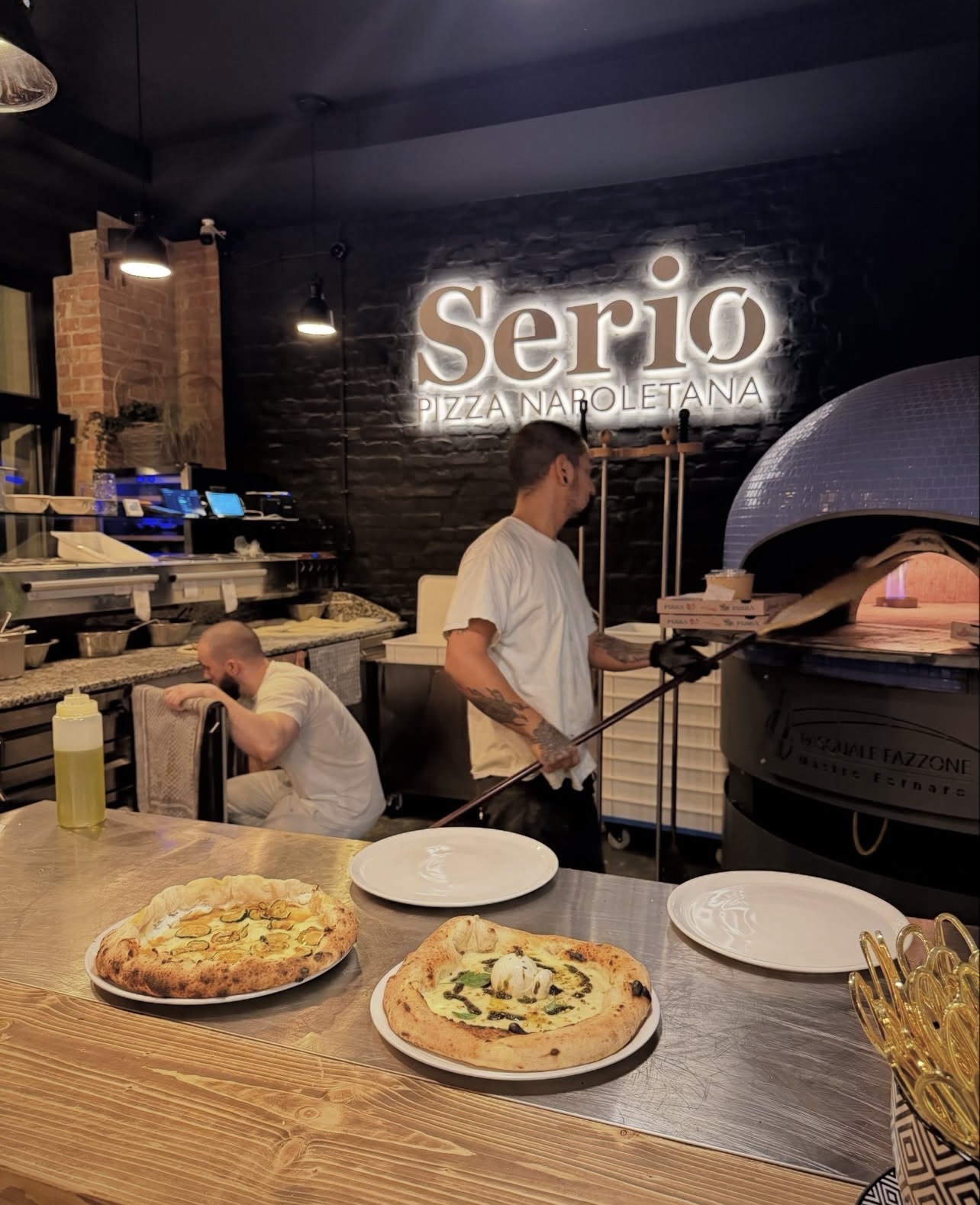 Pizzabäcker am blauen Holzofen mit Serio-Neon