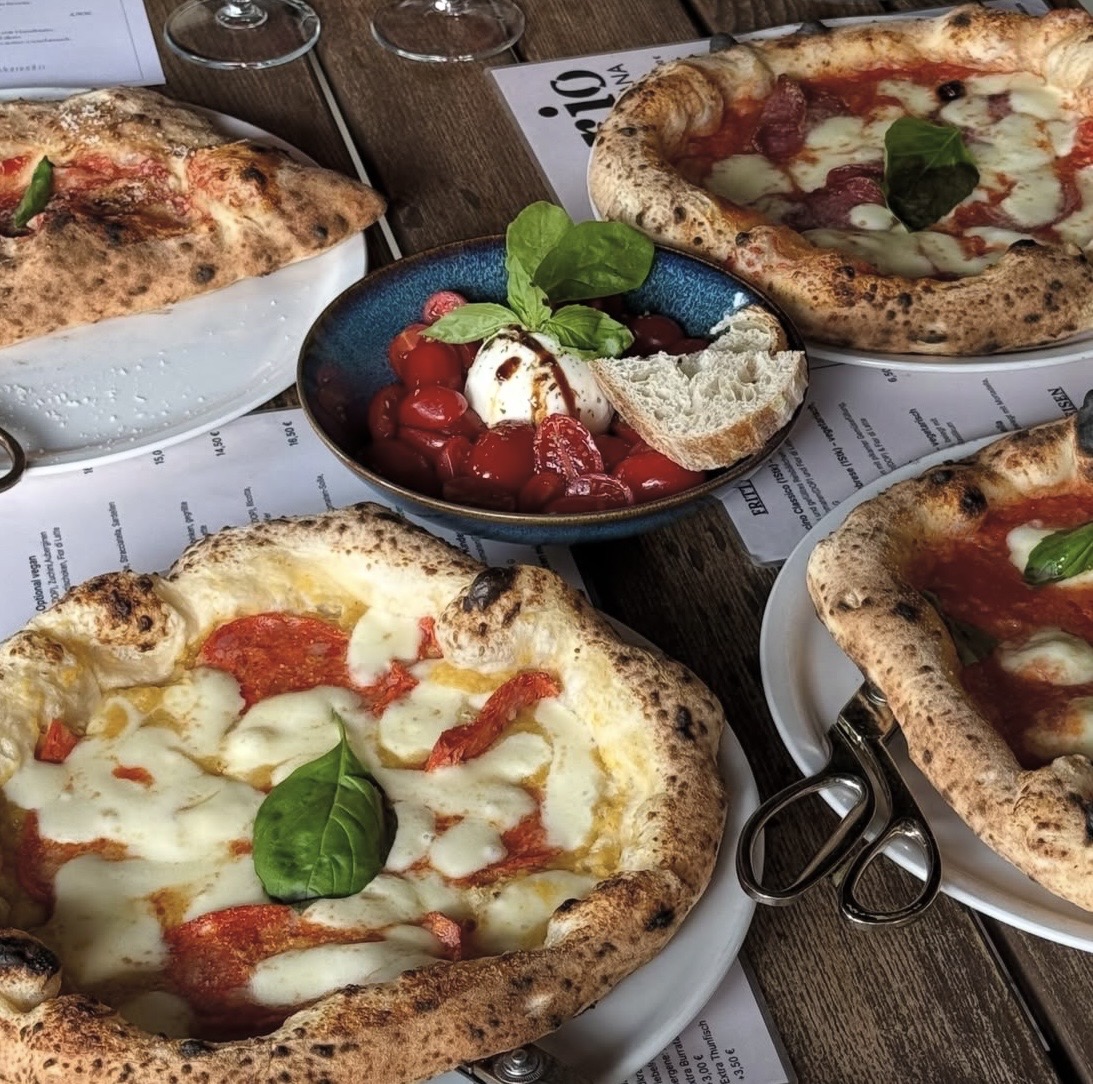 Tisch mit Pizzen, Burrata und Tomaten
