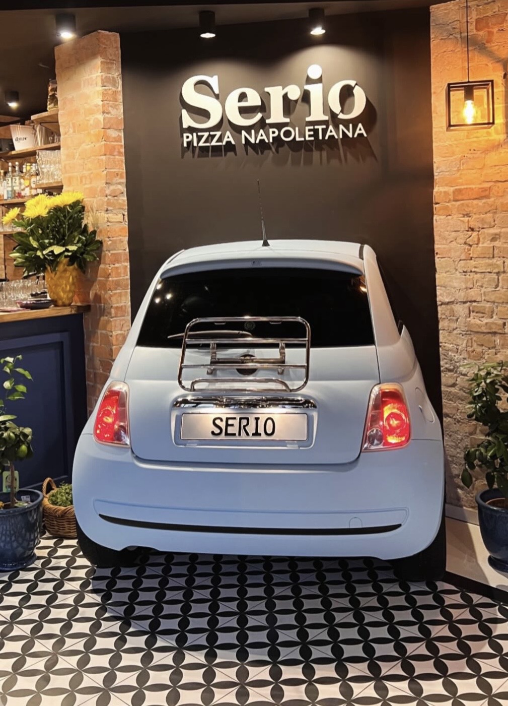 Hellblauer Fiat 500 im Restaurant vor Serio-Logo