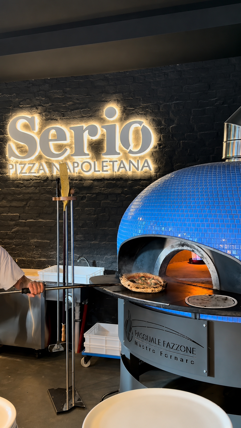 Pizzabäcker vor dem blauen Serio-Ofen mit leuchtendem Logo